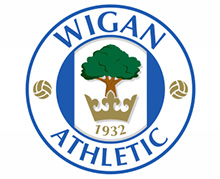 Wigan Athletic club logo with a green tree and crown design, featuring the name and year established.